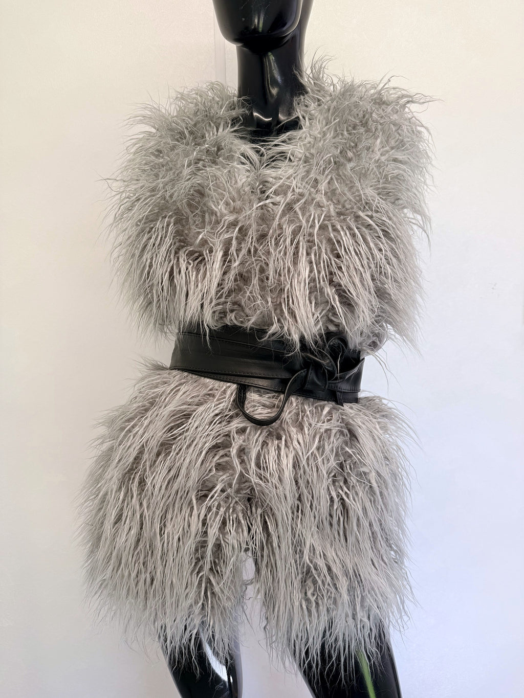 Black leather obi belt tied in a loop over a grey faux fur gilet on a mannequin