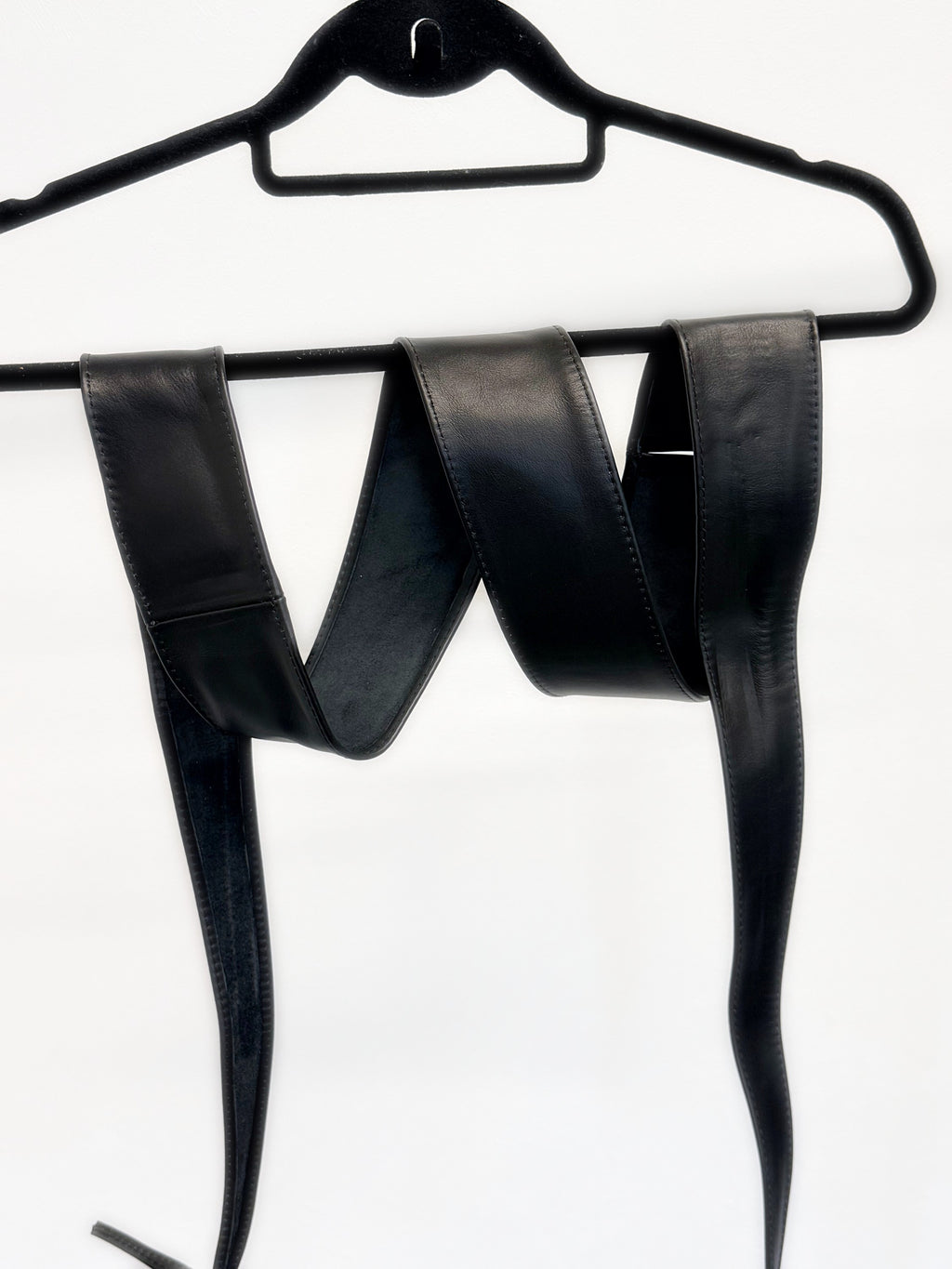 Full length of the black leather obi sash belt on a hanger