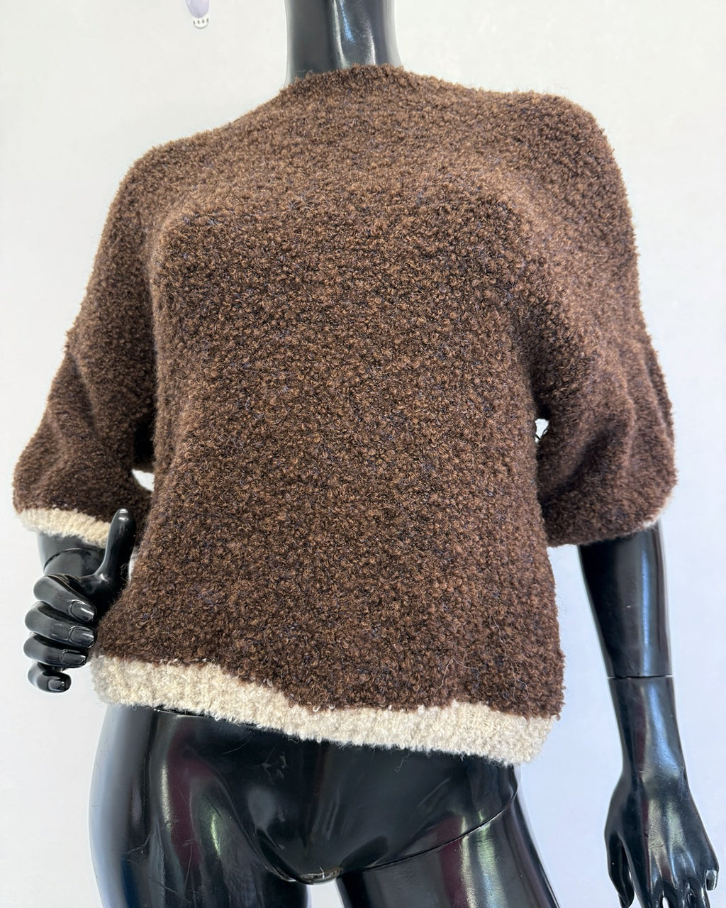 Brown and cream bouclé knit jumper on mannequin showing the elbow-length dolman sleeves and cream bouclé hem