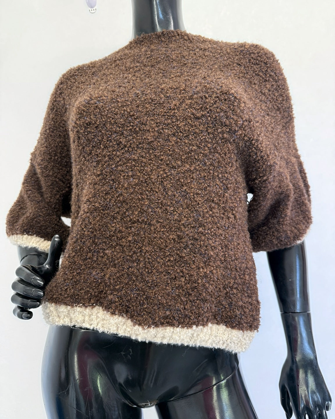 Brown and cream bouclé knit jumper on mannequin showing the elbow-length dolman sleeves and cream bouclé hem