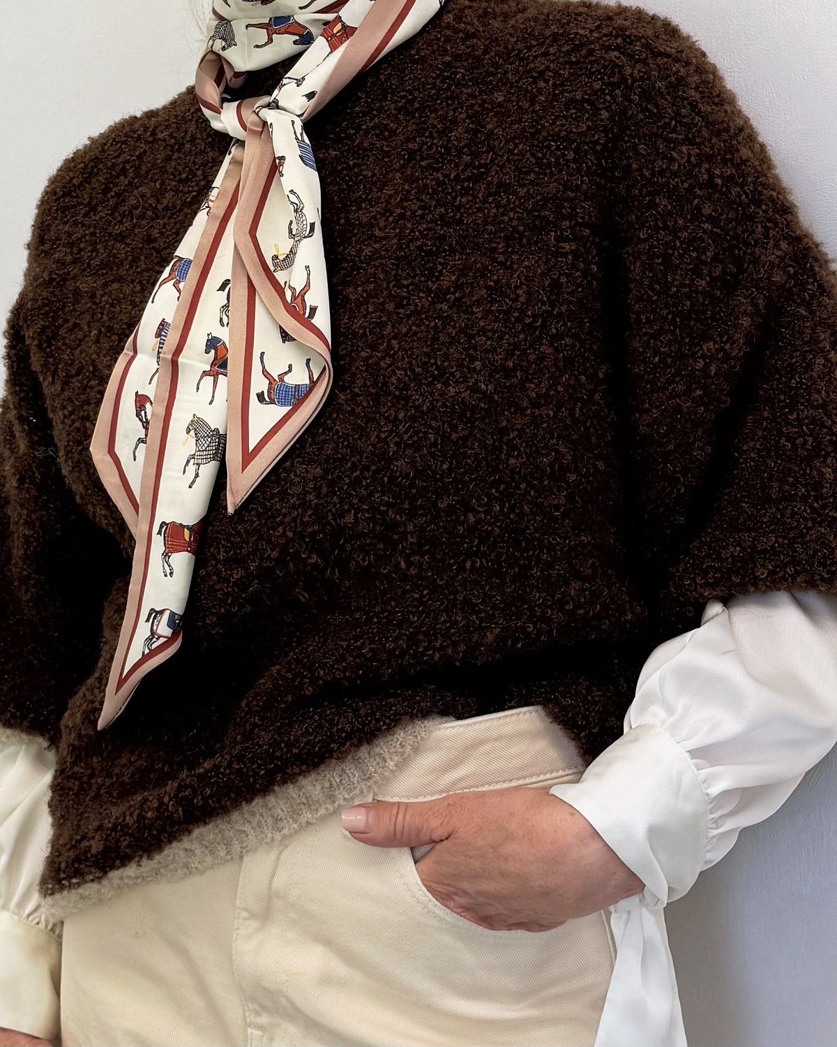 Close-up of the chocolate brown bouclé jumper with cream bouclé trim, styled with a silk scarf and white shirt