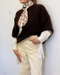 Brown and cream bouclé soft textured knit jumper worn over a white shirt with cream wide-leg trousers and a silk scarf