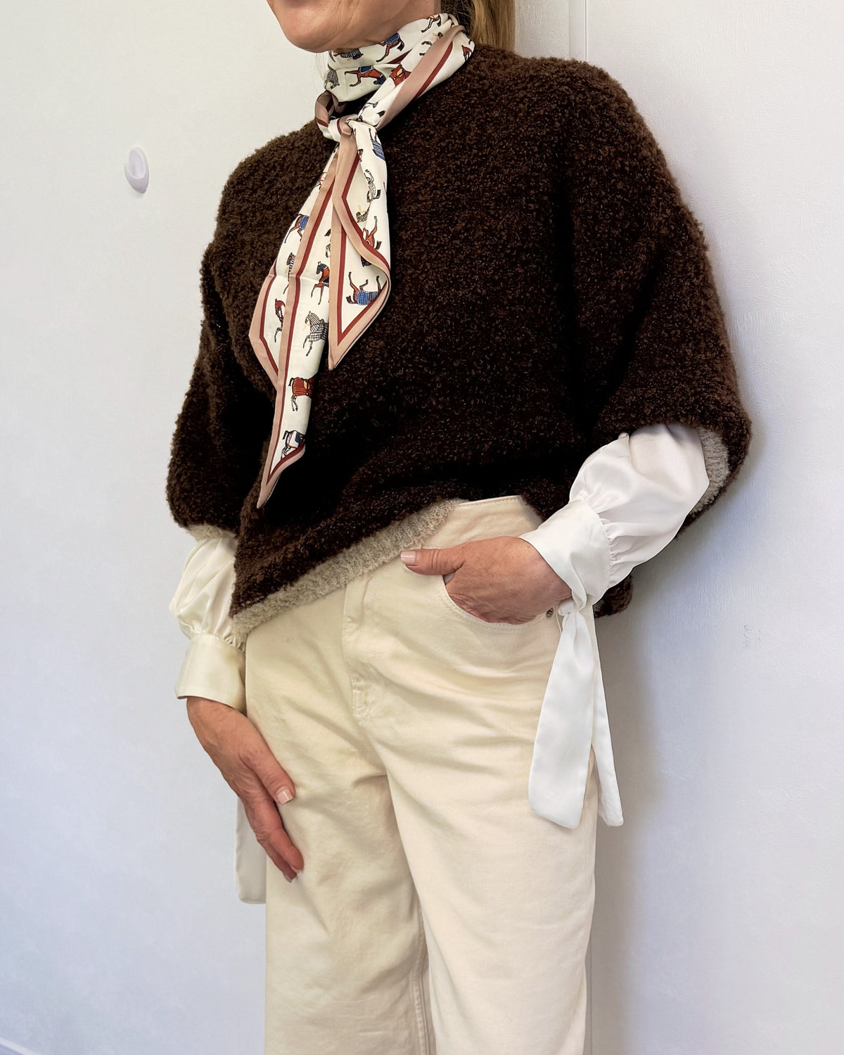 Brown and cream bouclé soft textured knit jumper worn over a white shirt with cream wide-leg trousers and a silk scarf