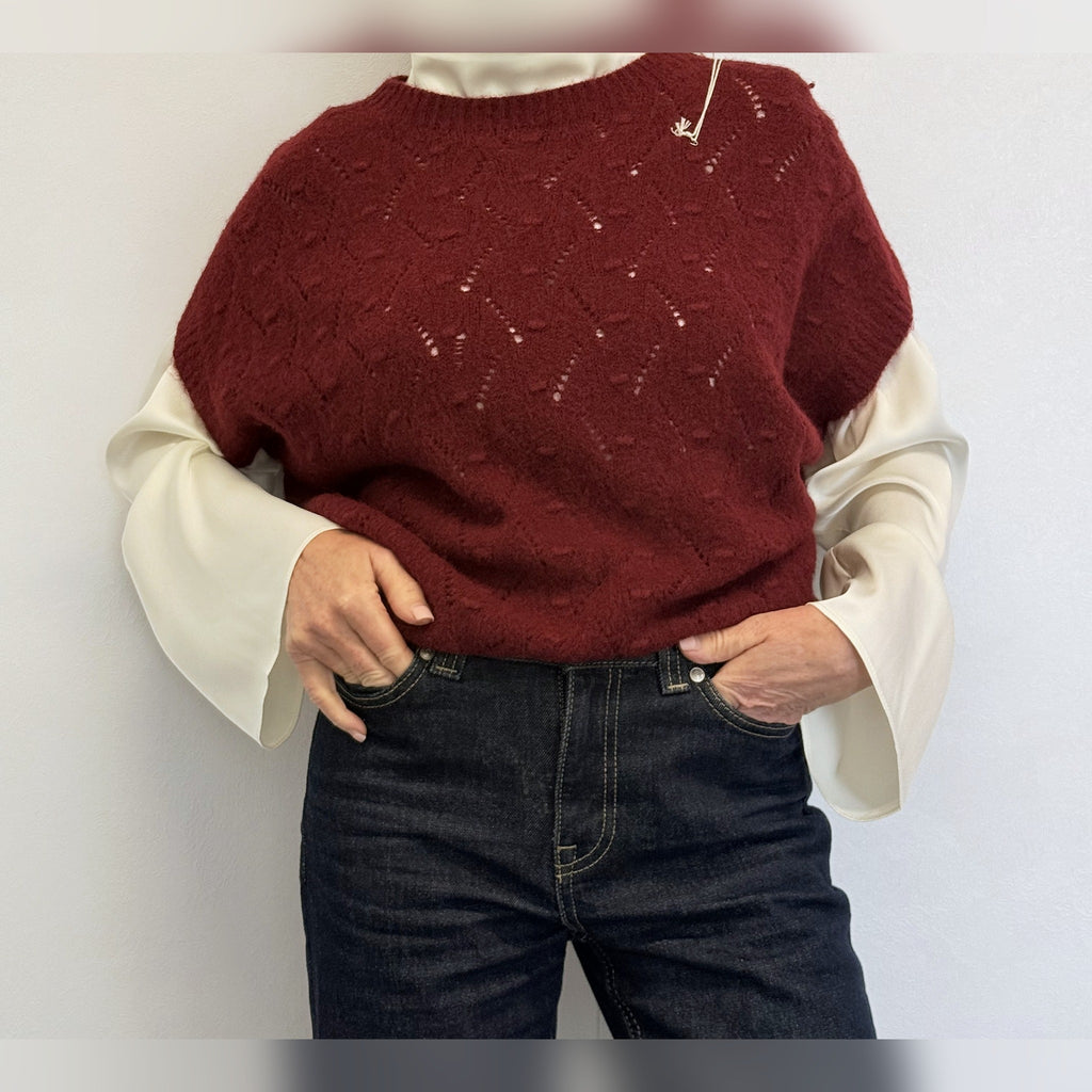 Burgundy knit tank top worn over a white statement-sleeve shirt with jeans, front