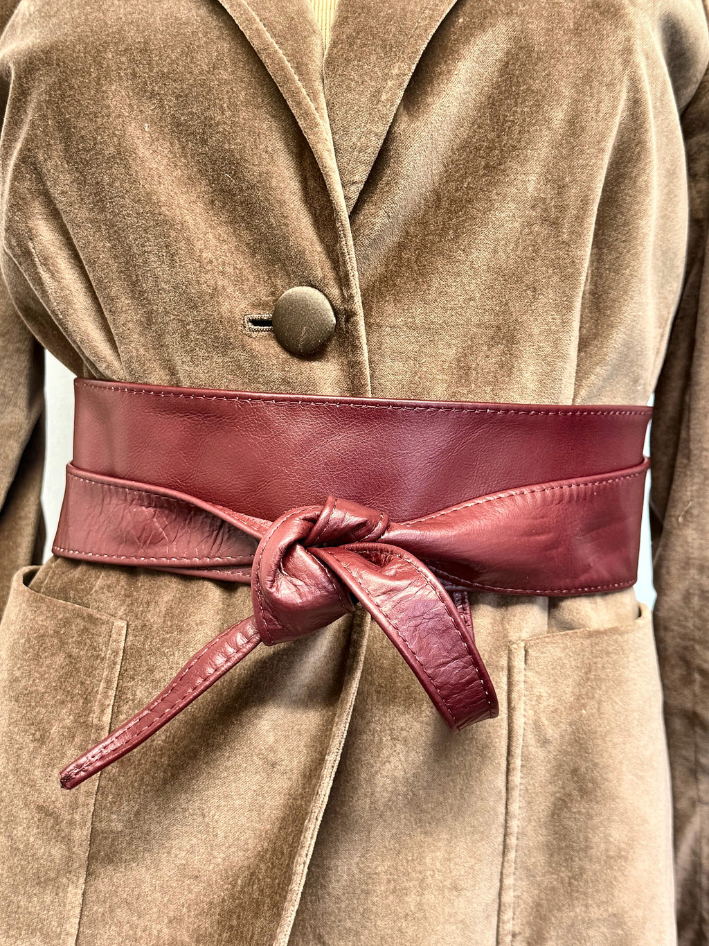 Burgundy leather obi waist tie belt knotted over a camel velvet blazer