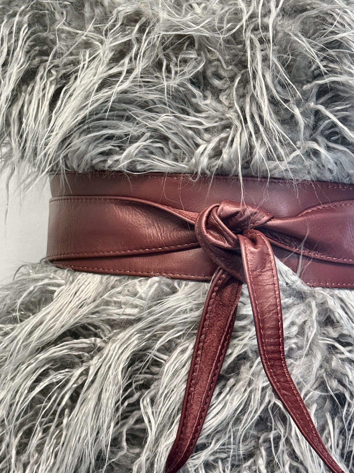 Burgundy real leather obi belt tied over a fluffy grey faux fur gilet