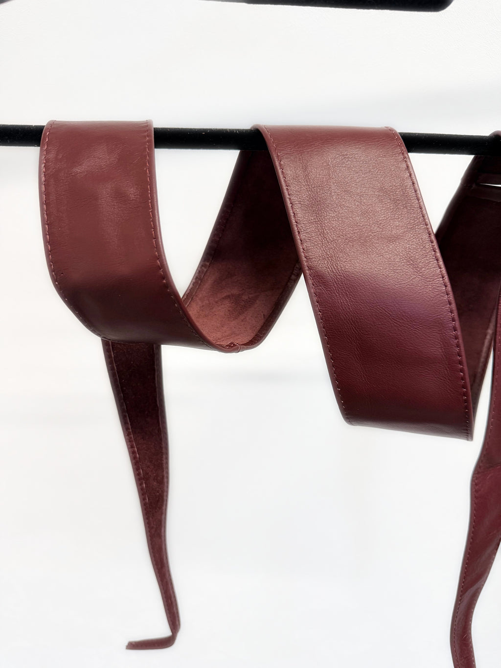 Burgundy leather obi belt on a hanger showing the long tie ends