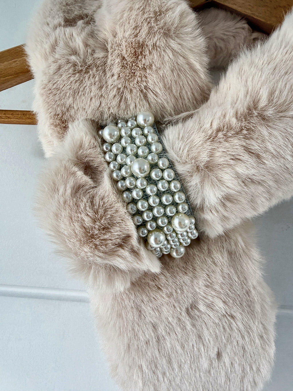 Close-up of the pearl loop brooch on the cream faux fur neck warmer