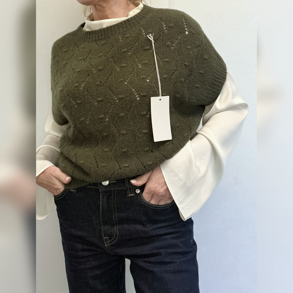 Khaki Forest Green knit tank top worn over a white statement-sleeve shirt with jeans, front