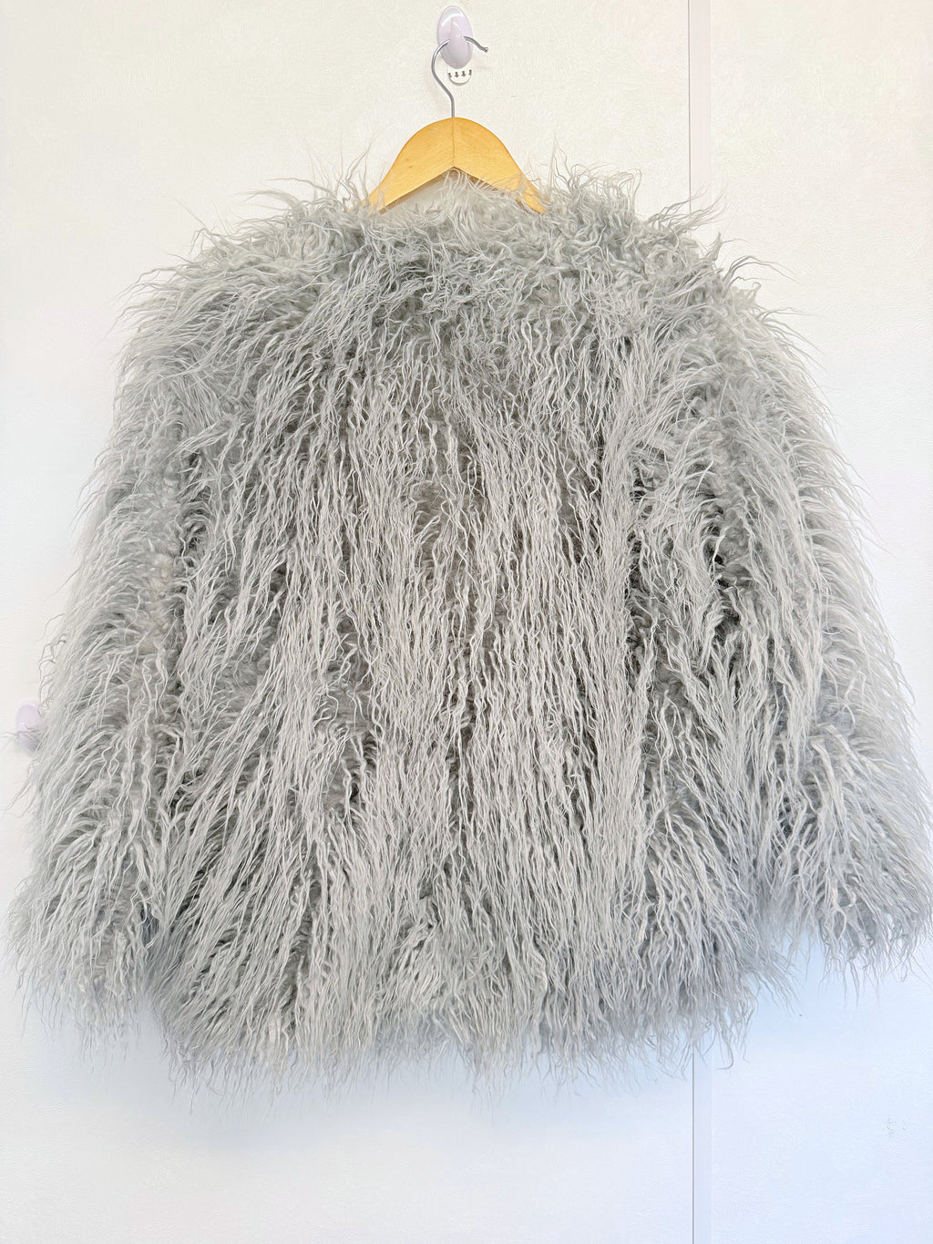 Light grey shaggy faux fur coat jacket on a hanger, front view