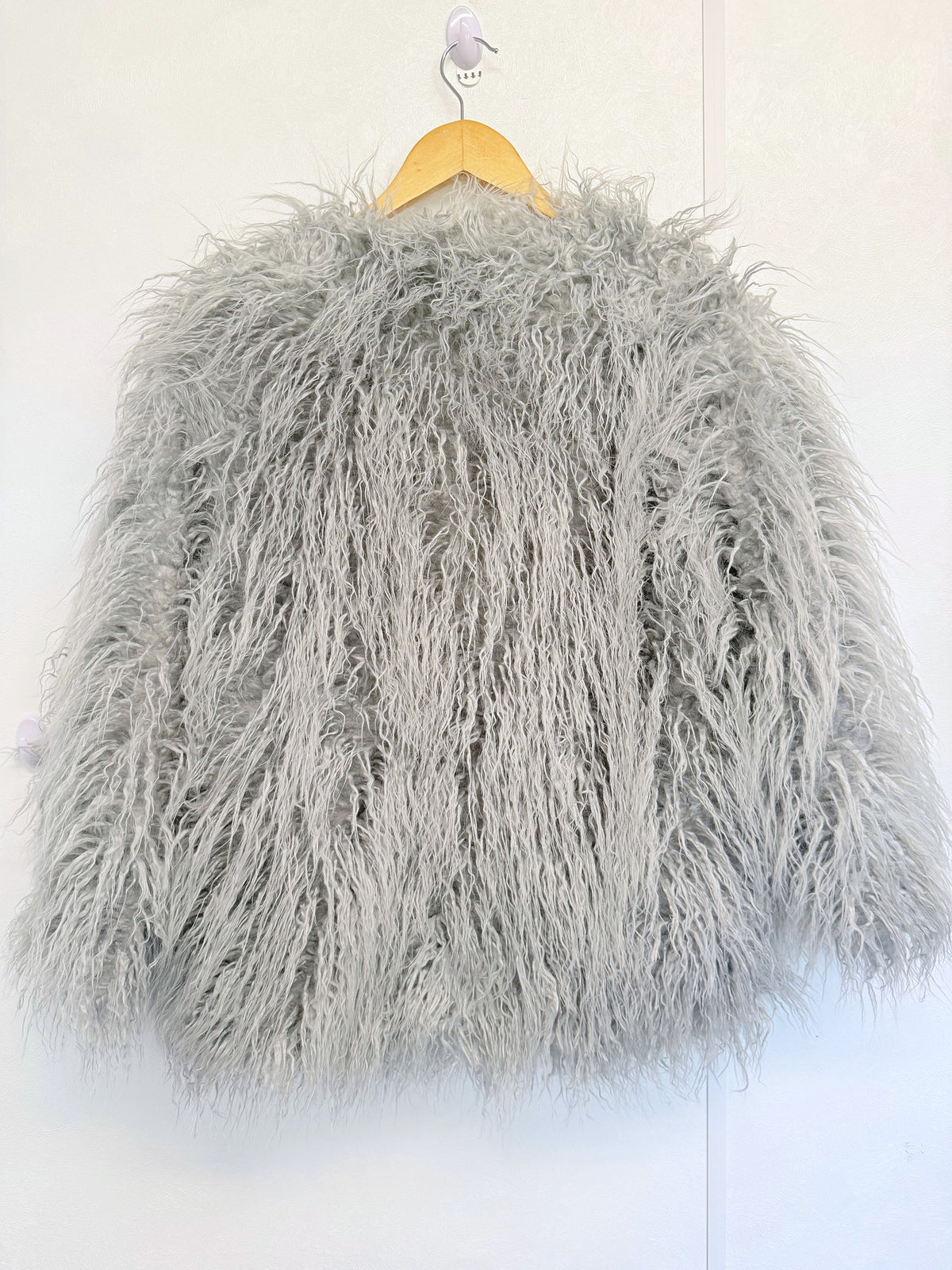 Light grey shaggy faux fur coat jacket on a hanger, front view