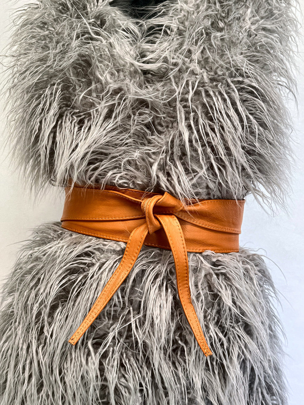 Tan leather obi belt tied over a fluffy grey faux fur gilet