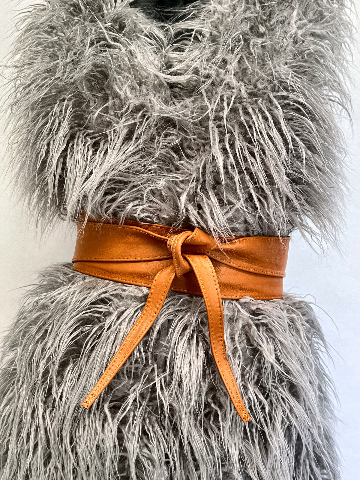 Tan leather obi belt tied over a fluffy grey faux fur gilet