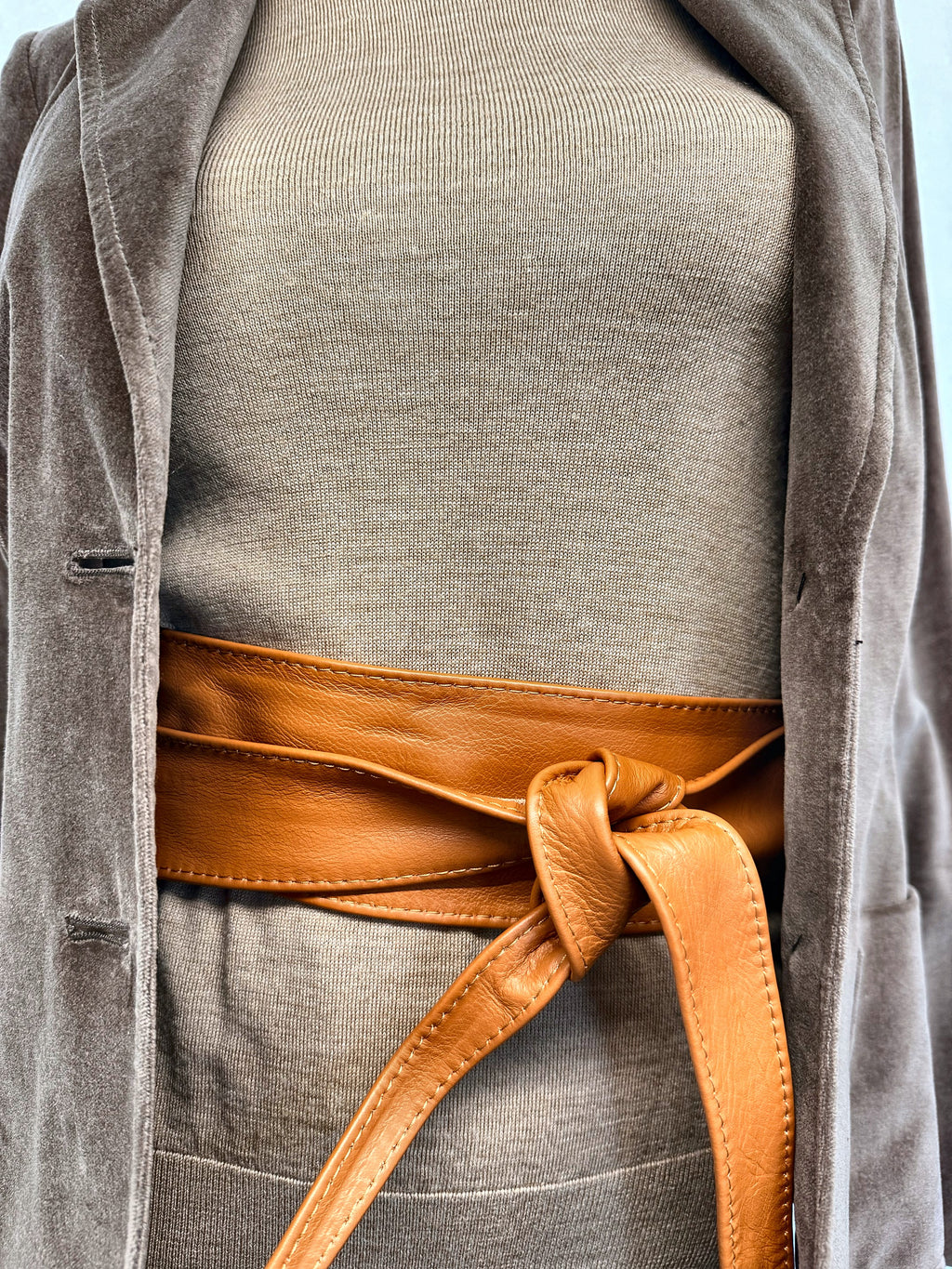 Tan leather obi waist tie belt over a knit jumper with an open velvet blazer
